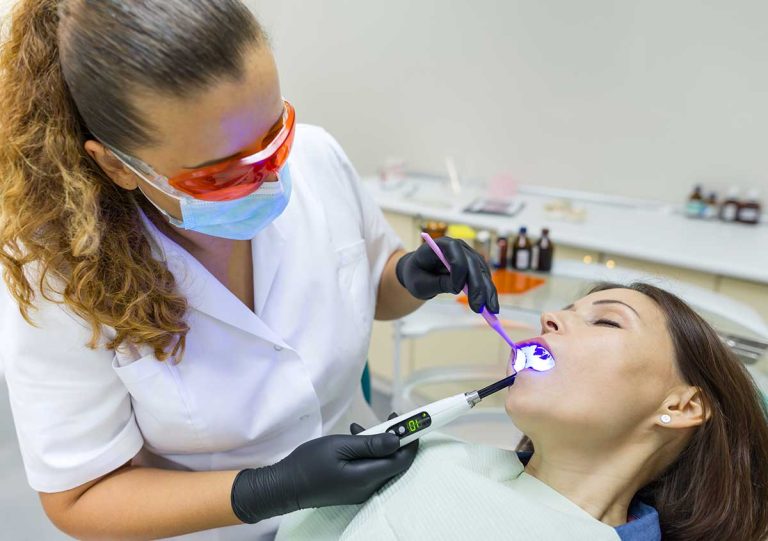 Adult female dentist treating patient woman teeth. Medicine, dentistry and healthcare concept
